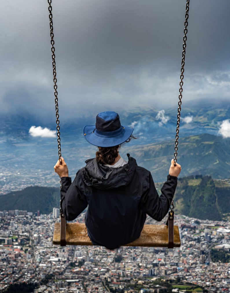 A student sits on the Swing in the Clouds on the slopes of Pichincha, looking over Quito, Ecuador.