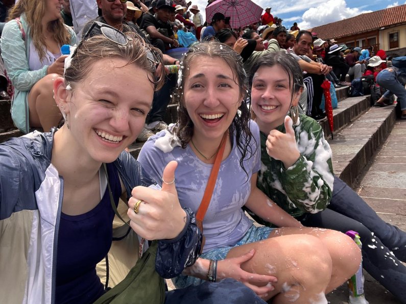 Three students laugh and give thumbs up while covered in water and suds.