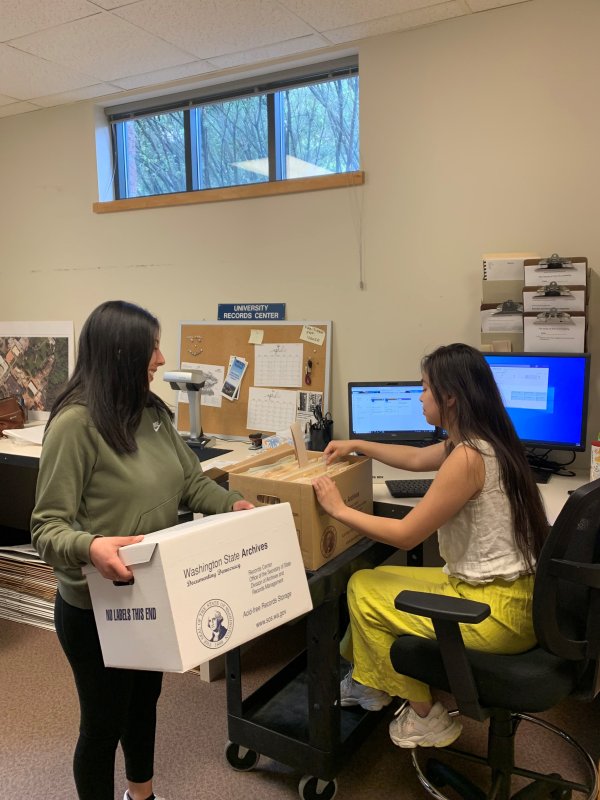 Two student employees working for University Archives & Records Management in an office in the Goltz-Murray Archives Building.