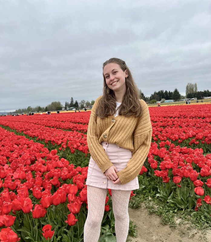 Elise Tahti stands in front of a field full of red tulips