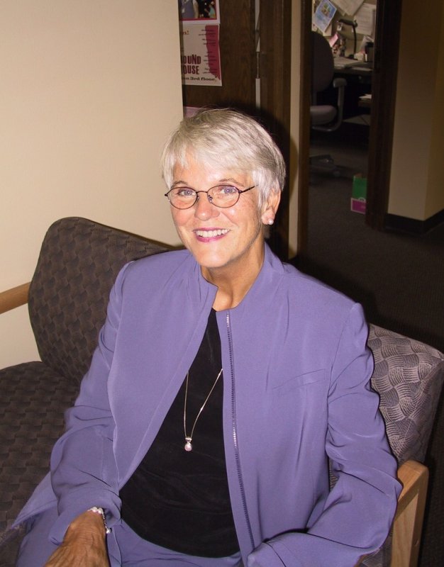 Kay Rich sits in a chair in her office and smiles at the camera