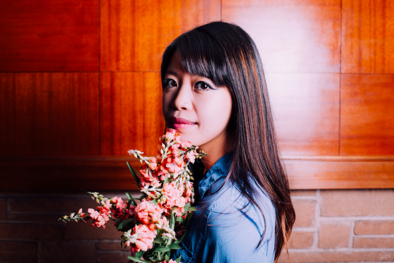Jane Wong looks at the camera holding a bouquet of flowers