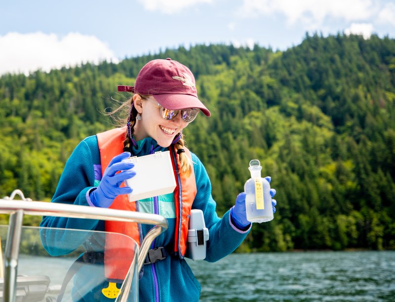  A student holds a sampling jar on a boat on Lake Whatcom