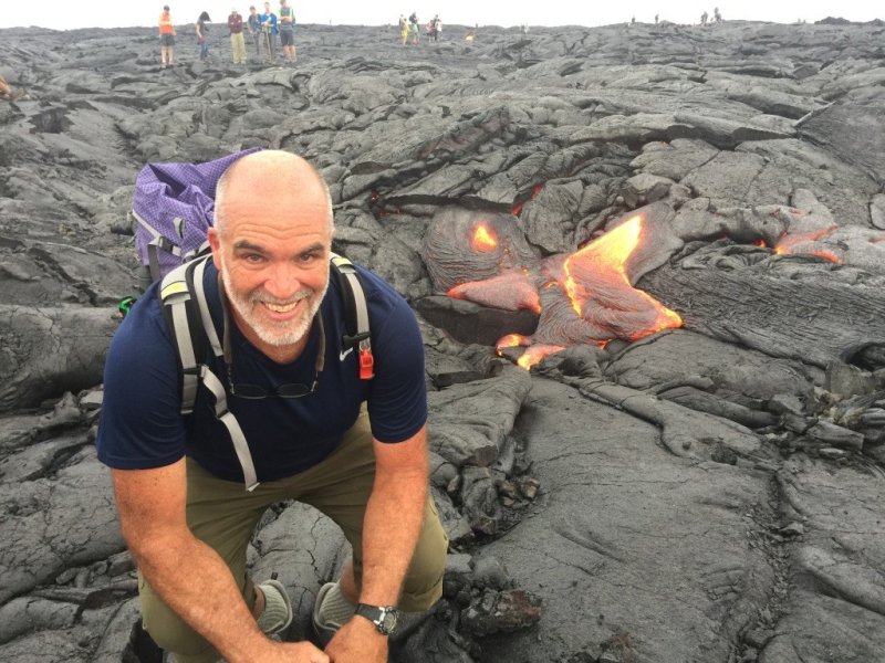 Michael Medler poses in a lava field in Hawaii; behind him is a glob of glowing lava