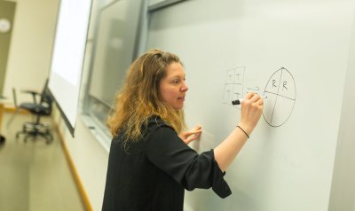 Jeanine Amacher writes in a white board during class