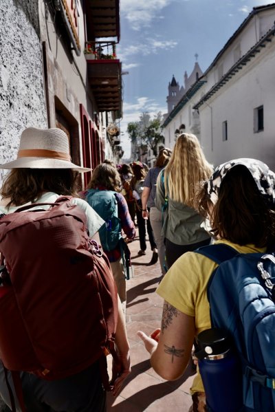 Students walk along the sidewalk as they explore the city of Cuenca on a sunny day.