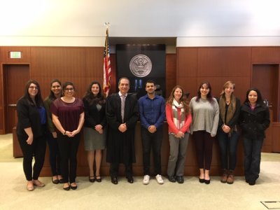Ceci Lopez and her students pose in a courtroom with federal judge Ricardo Martinez