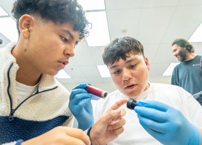 Kai Ibarra (left) and Junior Velazquez-Segovia examine a lens as they get ready to attach it to the microscope.