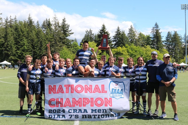  The image shows a group of male rugby players celebrating their victory in a tournament. They are holding a trophy and a banner that says "National Champion 2024 CRAA Men's DIAA 7s Nationals."