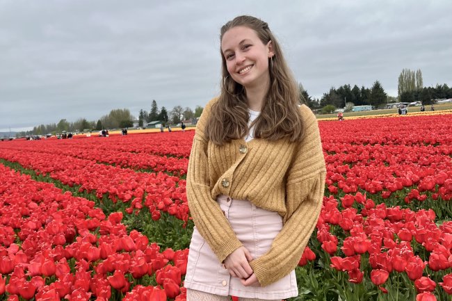 Elise Tahti stands in front of a field full of red tulips