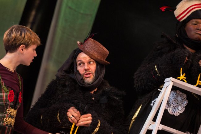scene from The Snow Queen with two actors dressed as imperious crows speaking to a  young girl