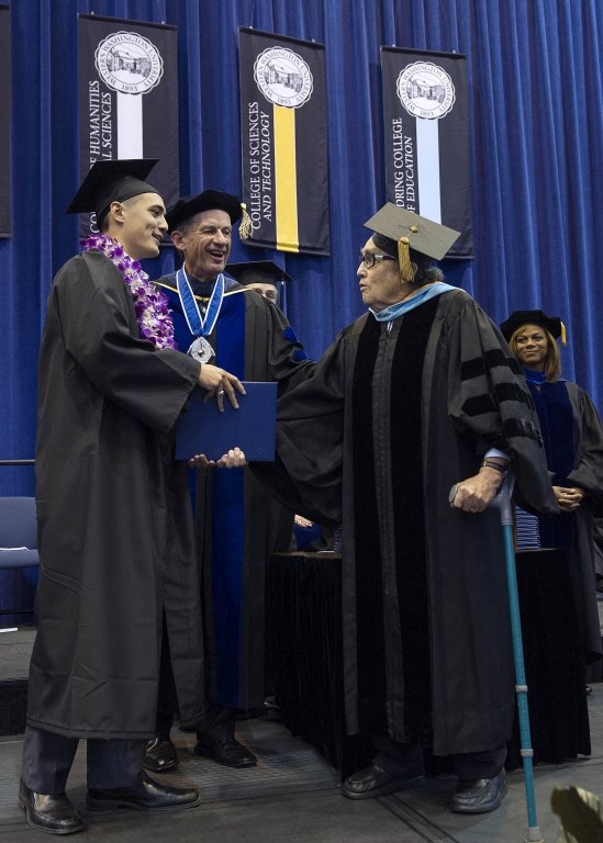 Former Western Washington University President Jerry Flora presents a diploma to his grandson, Addeson Moh. Photo by Dan Levine | for WWU