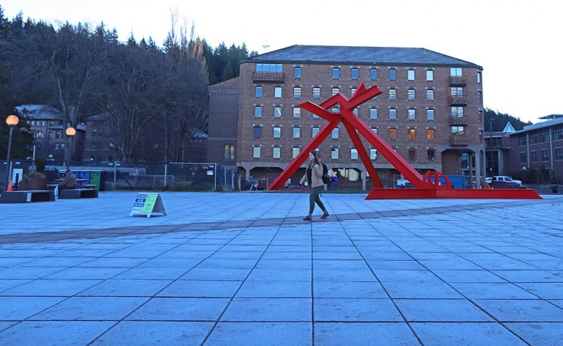 a student walks in front of the "For Handel" sculpture on a frost-covered plaza 