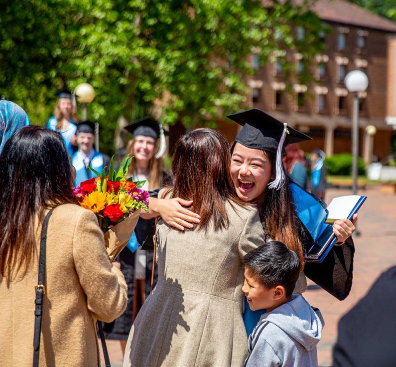 A new alumna hugs a family member in Red Square after commencement