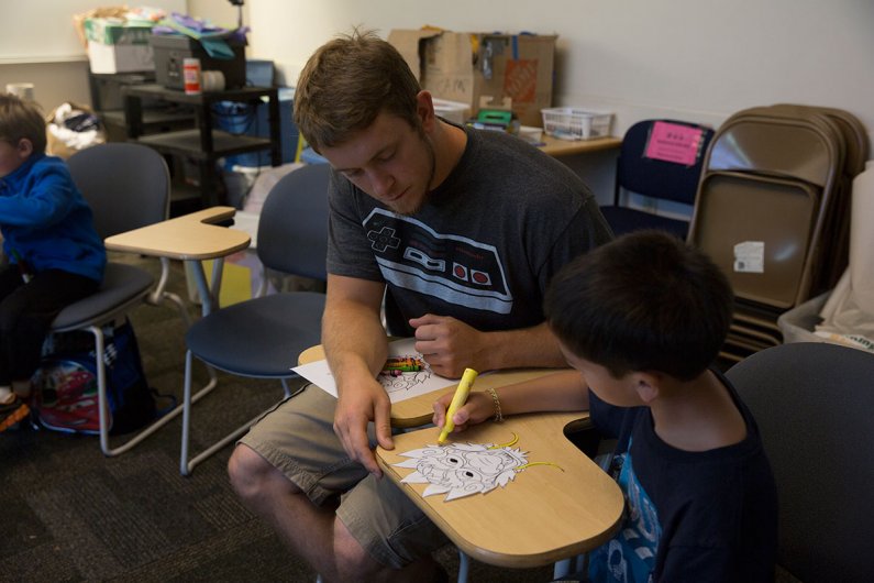 Western secondary science education major Nico Kniestedt helps a camper color in his dragon mask at Western’s Kids Camp on Tuesday, July 14, 2015. Photo by Alex Bartick / WWU Communications and Marketing intern
