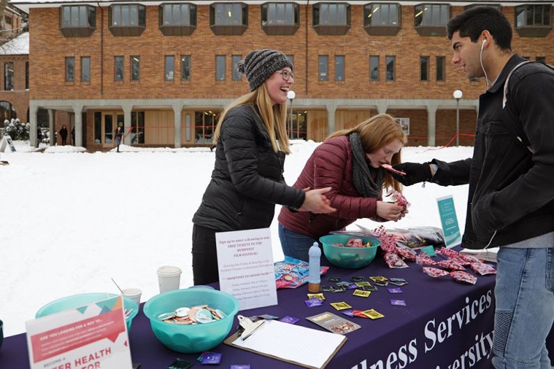 Junior Raia Stamm and sophomore Parker Hirks run the Prevention and Wellness Center's Valentine's Day booth in Red Square on Thursday, Feb. 14. The booth provides students with free contraception, information and candy. 