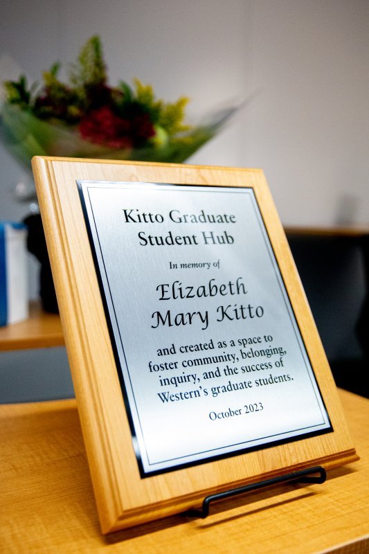 A plaque sitting on a table that has the words: “Kitto Graduate Student Hub, In Memory of Elizabeth Mary Kitto and created as a space to foster community, belonging, inquiry, and the success of Western’s graduate students. October 2023
