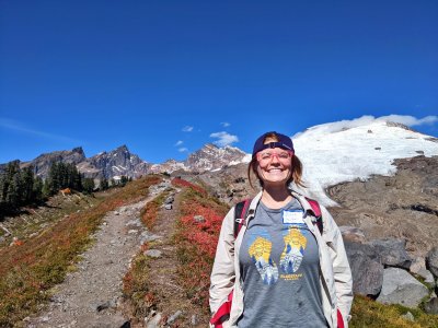 Jenna Chaffeur smiles on a mountain trail with blue skies in the background.