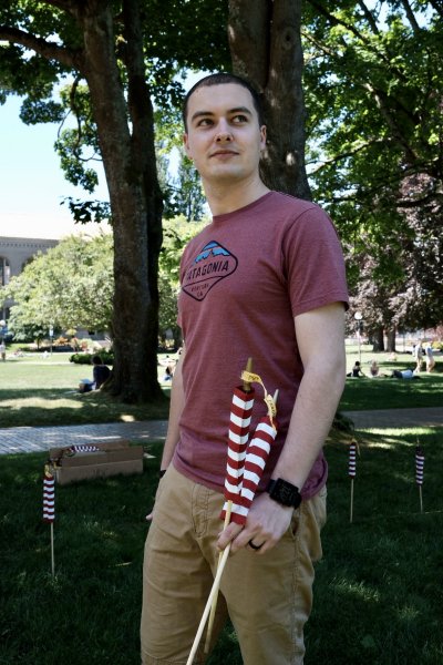 a student holds two flags that will be placed into the lawn in front of Old Main