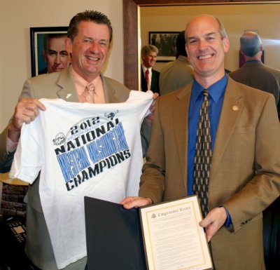 Western Washington University President Bruce Shepard holds up a T-shirt commemorating the university's NCAA Div. II men's basketball title, while Rep. Rick Larsen holds a resolution honoring the team that he introduced in the House of Representatives. Ph