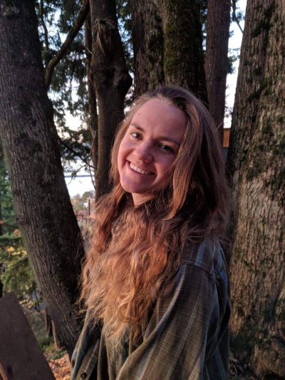 Piper Wolters smiles at the camera in a grove of trees